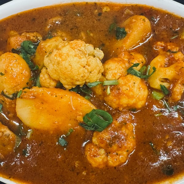 Close-up of Indian Aloo Gobi with potatoes and cauliflower in a rich, spicy curry sauce.