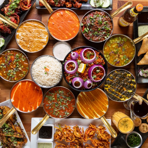 A top-down view of a large Indian food spread with various curries, rice, and appetizers.