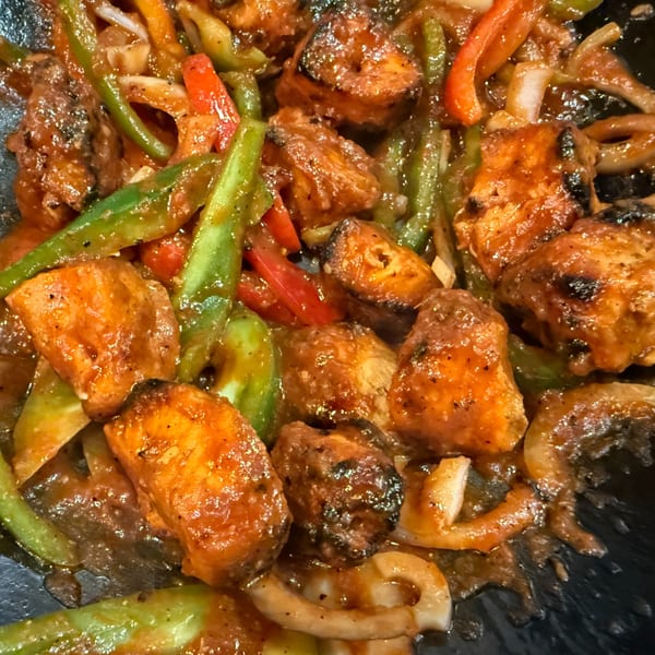 Close-up of Indian chili chicken with bell peppers and onions in a rich sauce.