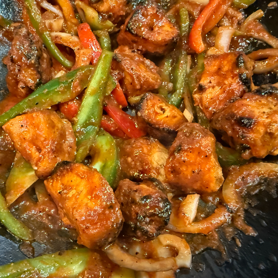 Close-up of Indian chili chicken with bell peppers and onions in a rich sauce.